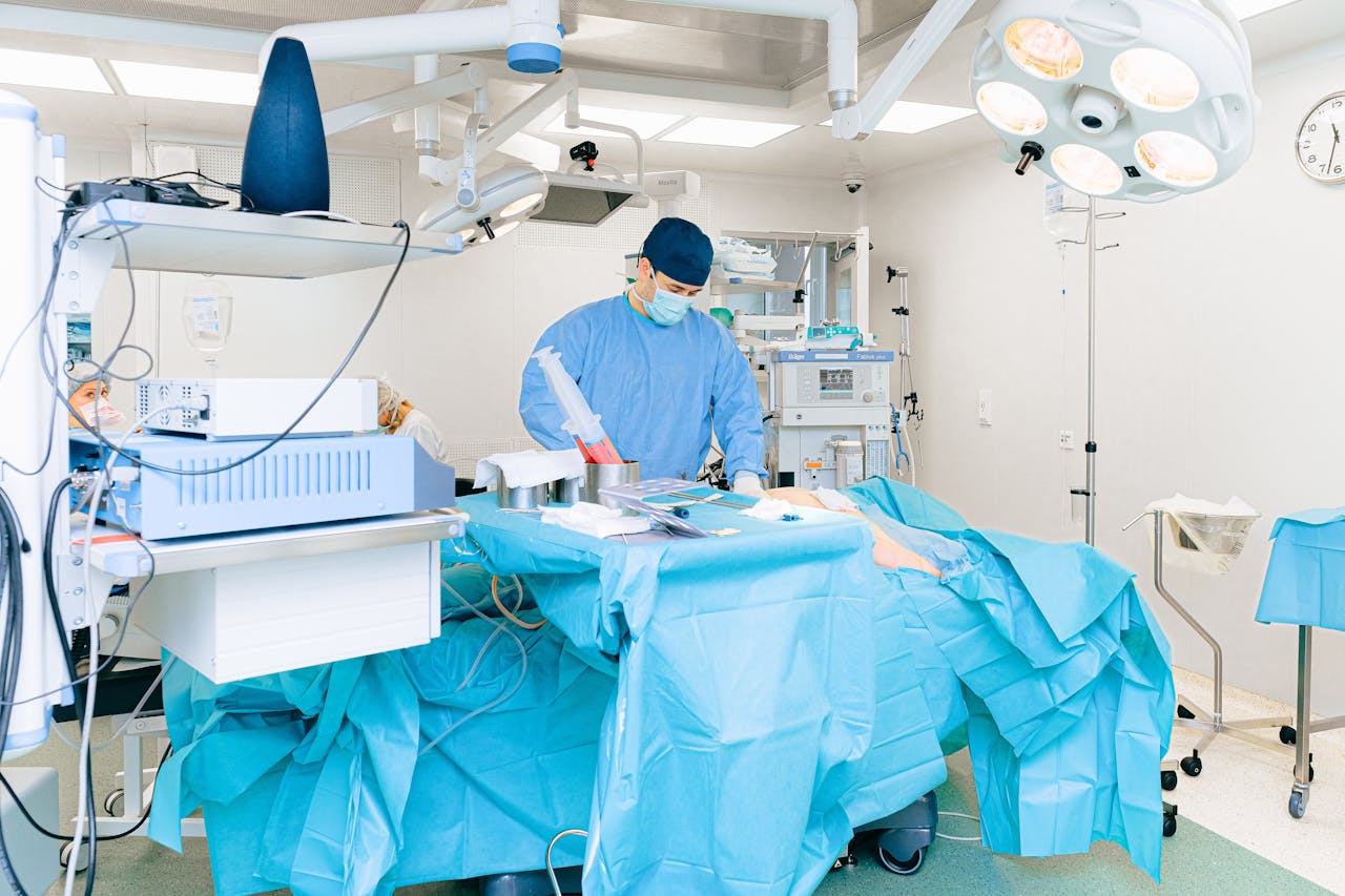 Doctor in surgical attire performing operation in a well-equipped operating room.